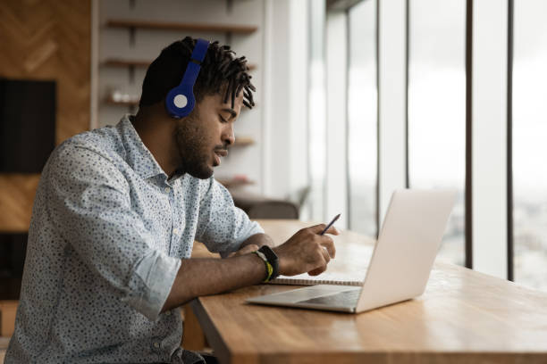 istock Side view African American man wearing headphones taking notes 1309810169