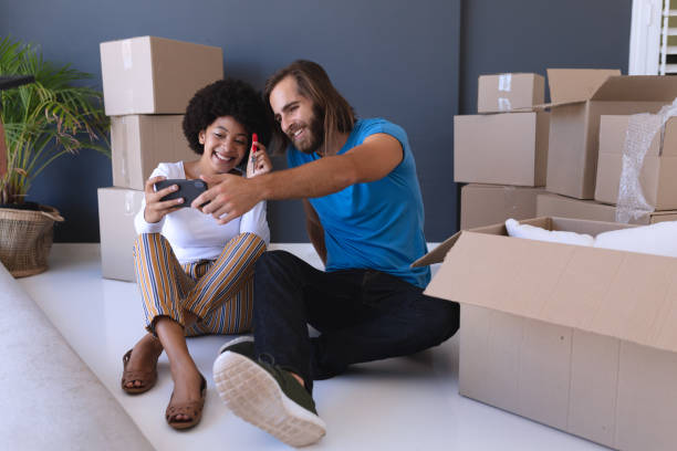 istock Happy diverse couple moving house sitting and using smartphone 1309810714