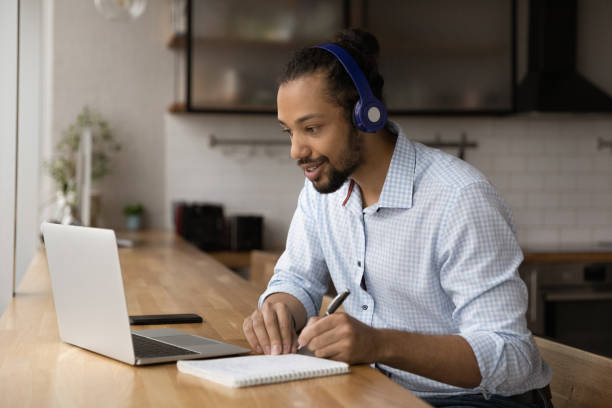 z bliska zmotywowany afroamerykanin ubrany w słuchawki oglądający seminarium internetowe - professional sport audio zdjęcia i obrazy z banku zdjęć