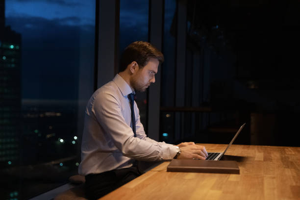 istock Side view confident businessman working on laptop at night 1309812968