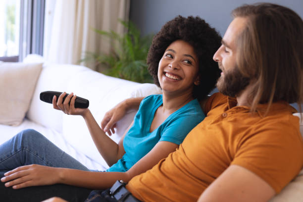 istock Happy diverse couple sitting on sofa embracing and watching tv 1309814518