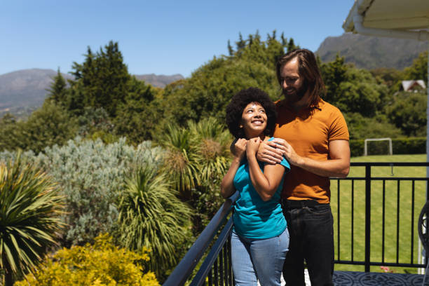 istock Happy diverse couple standing on balcony embracing and smiling 1309814778