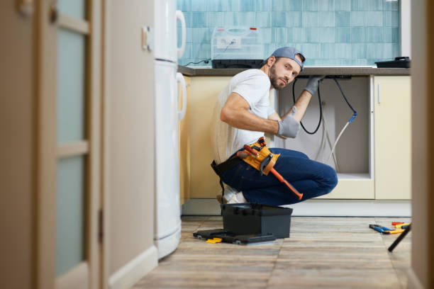 istock The work is done. Young repairman, professional plumber wearing tool belt looking at camera and showing thumbs up while crouching on the floor, fixing a pipe in the kitchen indoors 1309817444