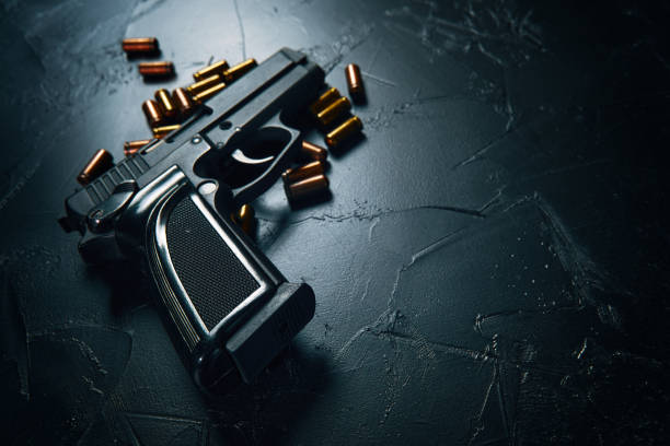 istock Gun with cartridges on dark concrete table. 1309820018