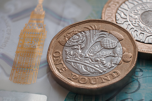 Moneda británica de una libra colocada en la parte superior del billete de polímero de 5 libras con visible símbolo del Big Ben. photo
