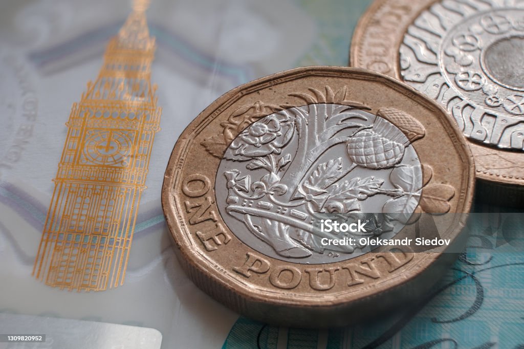 British one pound coin placed on top of polymer 5 Pound banknote with visible Big Ben symbol. Concept for banking, Finance and Economy of Britain. Selective focus. Macro. Selective focus. Macro. British Currency Stock Photo