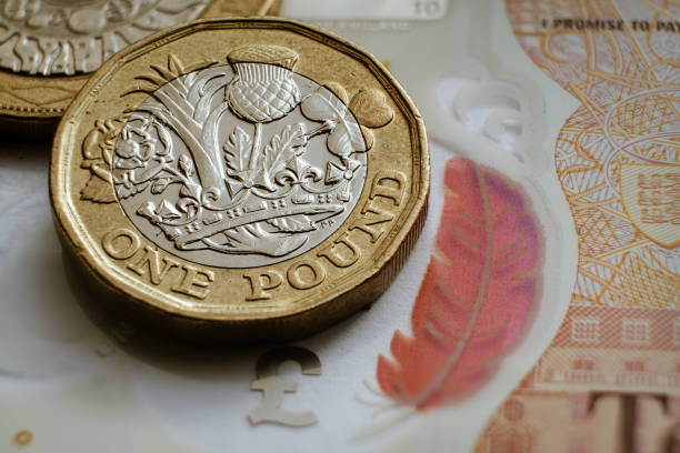 monedas británicas de una libra colocadas en la parte superior de billete de 10 libras. - british coin coin falling british currency fotografías e imágenes de stock