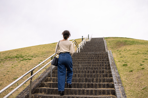 Young woman visiting places to enjoy viewing cherry blossoms, which is very popular activity in Japan in springtime.