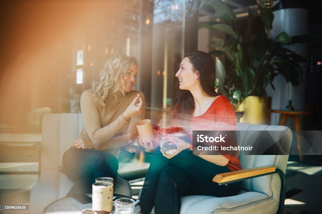 Female friends relaxing in the cafe Two female friends sitting in the cafe, spending the afternoon together, gossip, talk, relax, have coffee. Adult Stock Photo