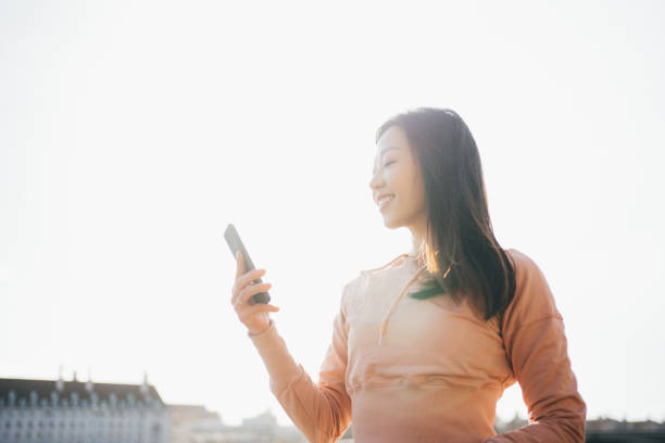 istock Asian young cheerful woman using her smartphone by the river side 1309825439