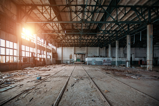 Abandoned ruined large industrial hall with garbage waiting for demolition.