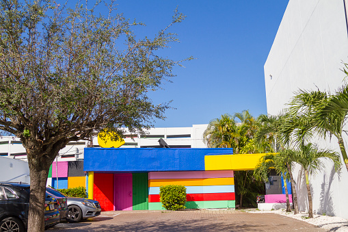 Miami, Florida, USA - December 26, 2020: A landscape view with a colorful modern contemporany building at Miami Design District.\n\nThe Design District, is a neighborhood within the city of Miami, Florida, United States, USA home of many flagship luxury stores including Hermès, Tom Ford, Louis Vuitton, Christian Louboutin, Prada, Celine and much more. An Art Neighborhood in Miami Florida which has a strong art culture presence and murals can be seen everywhere. Many stores was affected by Corona Virus Pandemic Illness and closed their business.\n\nThis Picture was taken as a Photojournalism Style.