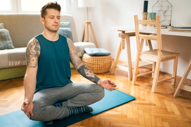 istock Young man holding hands in mudra while meditating at home 1309834999