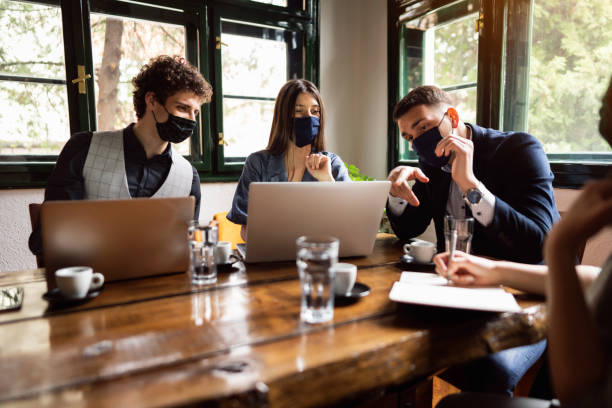 istock Young businesspeople wearing protective face masks while using laptops on a meeting 1309835848