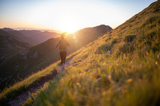 A shot of an young fit woman running in the mountain at sunset,