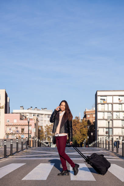 istock young woman pulling suitcase talking by phone 1309836254