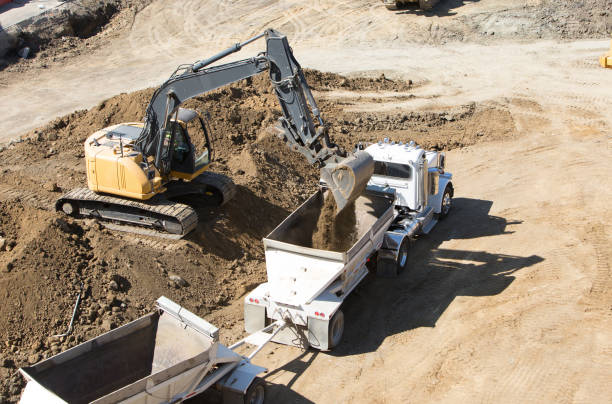 Construction site with excavator loading soil into dirt hauler truck trailer (dump truck) stock photo
