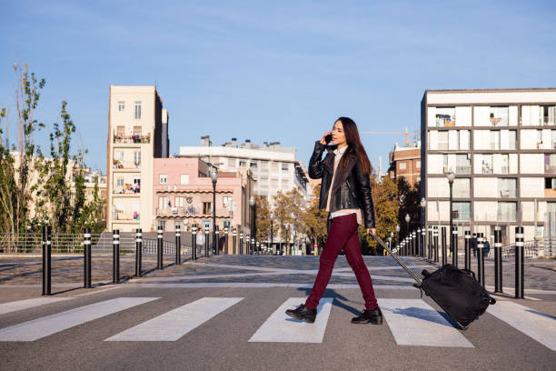istock young woman pulling suitcase talking by phone 1309844571
