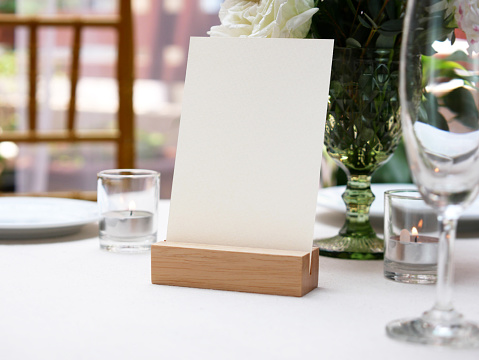 Mockup white blank space card, for greeting, table number, wedding invitation template on wedding table setting background. with clipping path