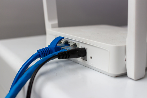 White wi-fi router with blue and black wires on white background