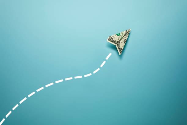 US Dollar Bill Paper Airplane with Dotted Chalk Path Creative Idea on Blue Background