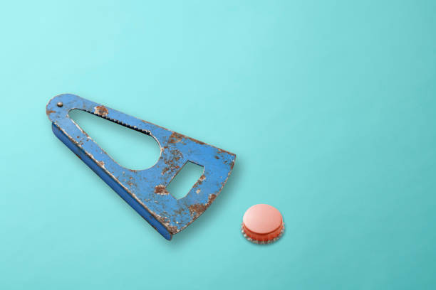 Hight angle view of old blue bottle opener with bottle cap on light blue background.