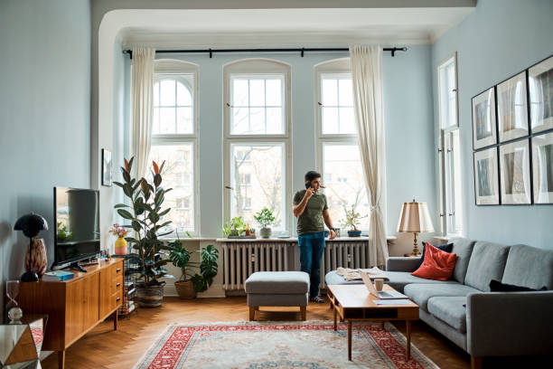 istock Man Talking On Mobile Phone Against Window At Home 1309848719
