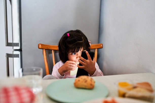 istock Cute Girl Using Mobile Phone In Kitchen 1309849293