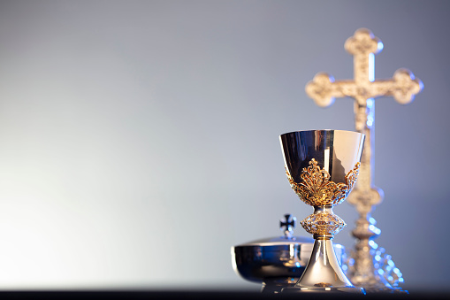 The Cross, monstrance  and golden chalice on blue background.