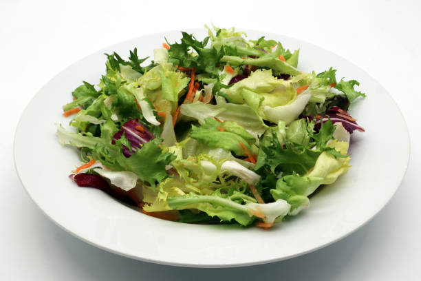 istock Fresh mixed green salad in a bowl isolated on white 1309864070