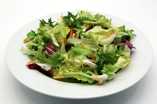 Fresh mixed green salad in a bowl isolated on white background