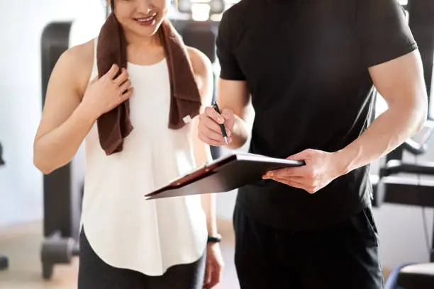 Photo of Asian male personal trainer giving training advice