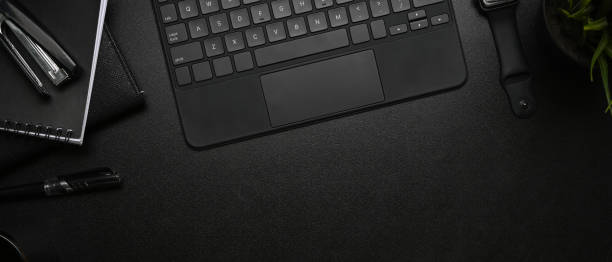 istock Horizontal image of modern dark workplace with smart watch, keyboard and notebook on black leather. 1309864892