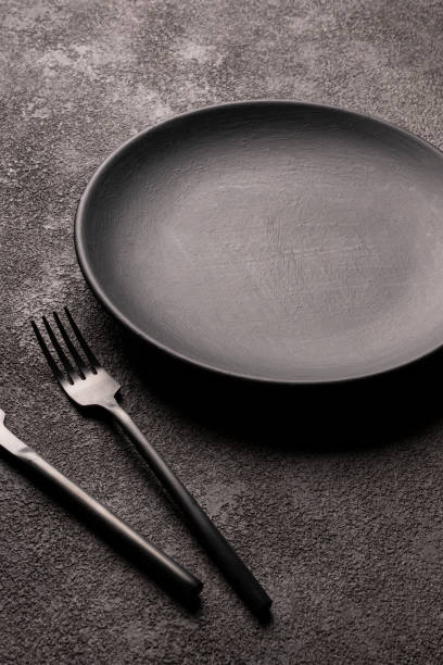 istock a frosted black empty plate and a knife and fork. concept for restaurant decor vertical photo, cutlery on a dark background 1309864912