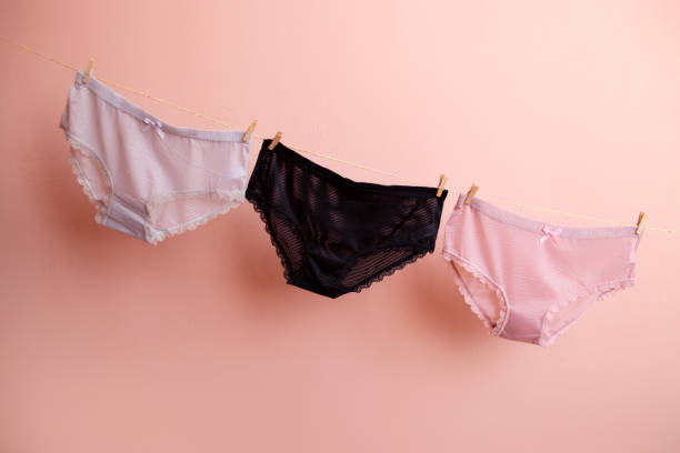 coloridas bragas limpias para mujer cuelgan de una cuerda. sobre un fondo aislado rosa - biquini fotografías e imágenes de stock