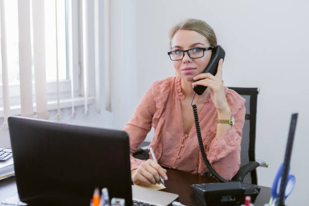 istock Everything is in work. Office worker woman talking on the phone while sitting at the table with a laptop in the office 1309868043