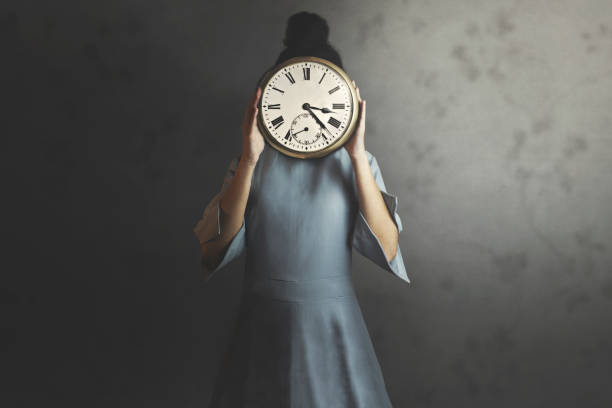 istock woman holds a clock in front of her face 1309871501