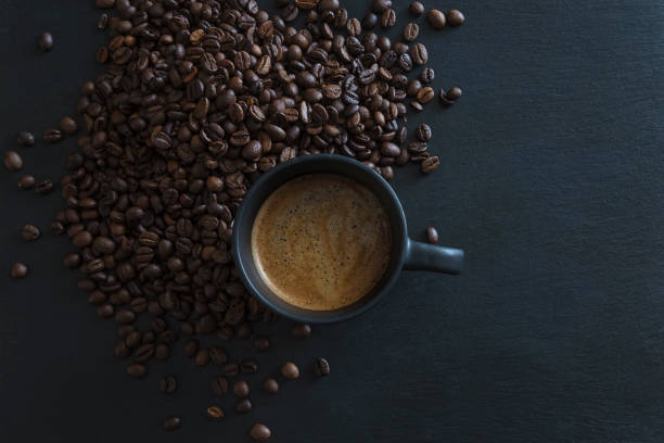 istock Black cup of coffee and roasted coffee beans on black slate 1309873283