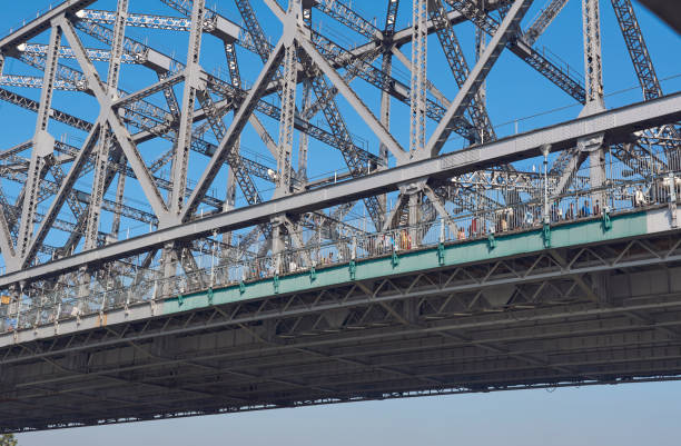 View of iconic Howrah Bridge (Rabindra Setu) of Kolkata over Ganges river, from a ferry boat. One of the world's busiest cantilever bridge, people are seen walking on the bridge. Everyday more than lakhs of people use this bridge which connects two cities, Howrah and Kolkata.