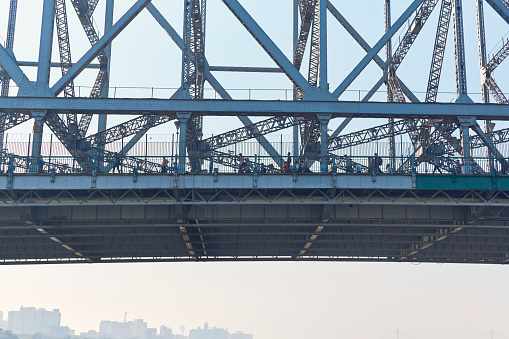 View of iconic Howrah Bridge (Rabindra Setu) of Kolkata over Ganges river, from a ferry boat. One of the world's busiest cantilever bridge, people are seen walking on the bridge. Everyday more than lakhs of people use this bridge which connects two cities, Howrah and Kolkata.