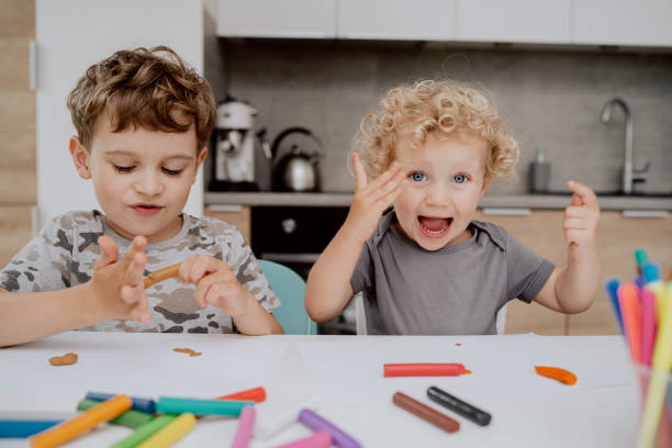 istock The happy siblings are sitting at the kitchen table playing with plasticine. A school-aged boy and a preschool-aged girl spend their free time together 1309879280