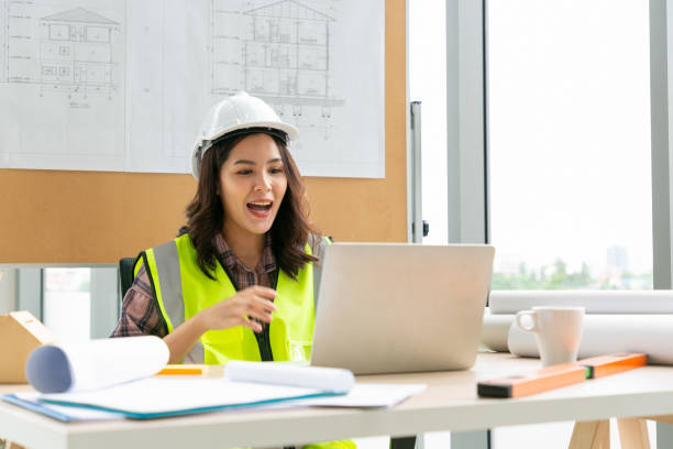 istock Young engineers waving while having online meeting over laptop at office. 1309880168