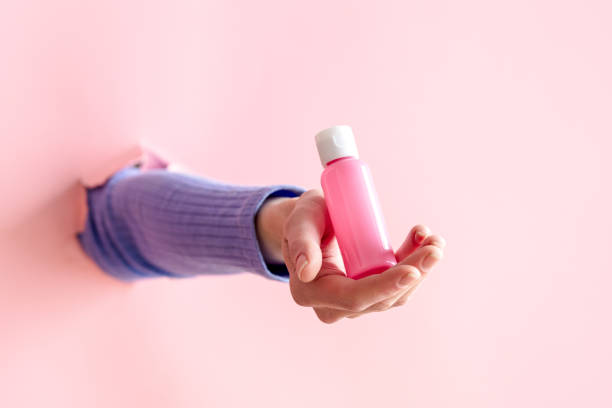 istock female hand hold cosmetic bottle on pink background. 1309880465