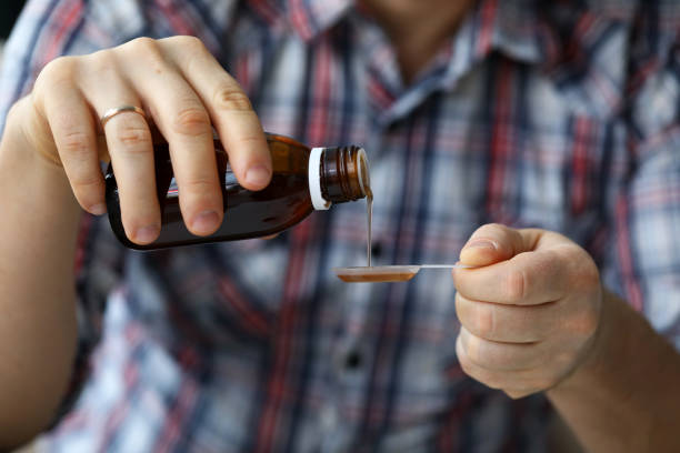 istock Sick man holding in hands vial with syrup close-up 1309880591