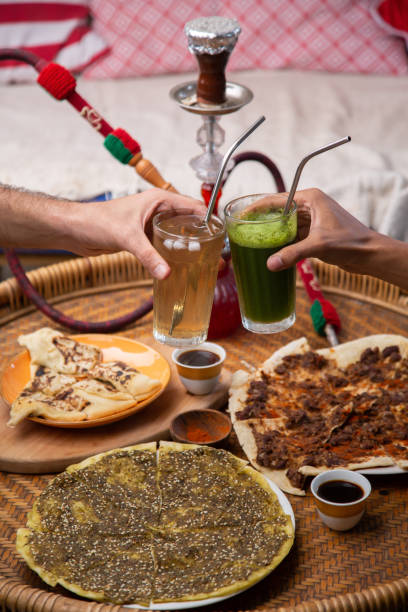 istock Close up of people's hands cheering drinks over table with Middle eastern or arabic dishes, assorted meze and hookah 1309882655