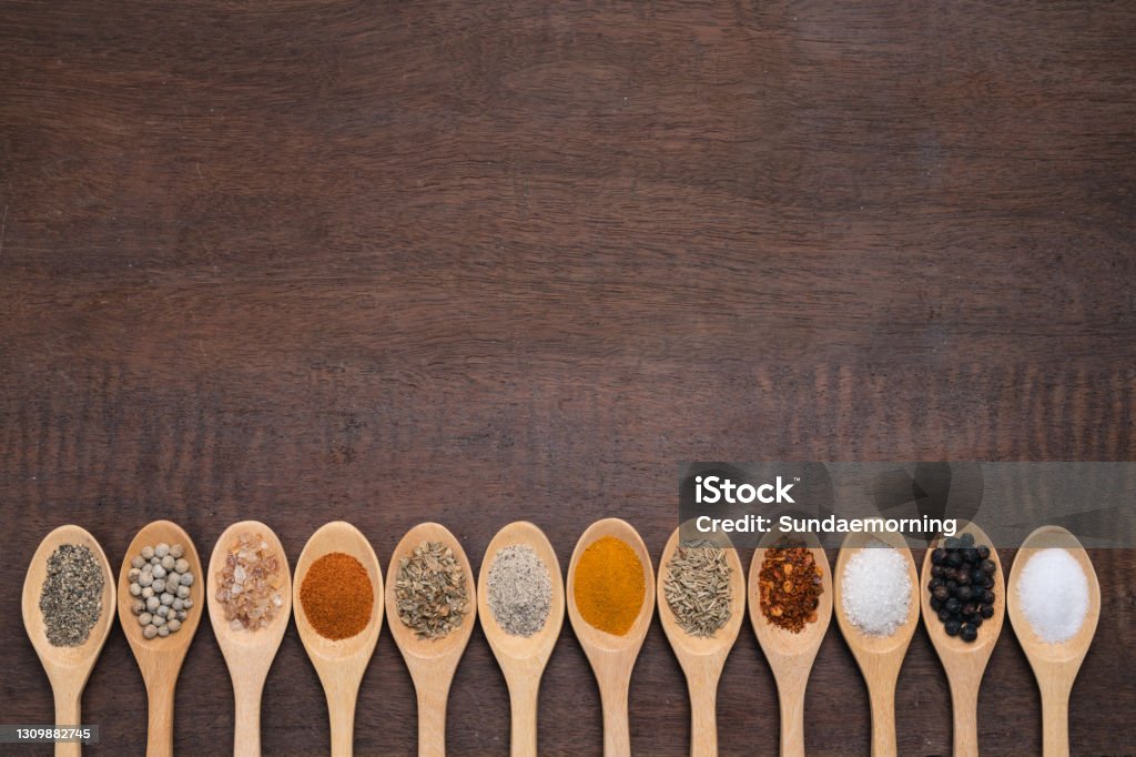 Various spices in wooden spoon on wood table background, sugar, pepper, salt, turmeric, rosemary, oregano, copy space Celery Stock Photo