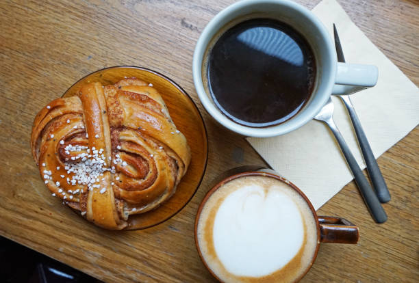 Fabrique cinnamon bun served with hot black coffee and Latte Western food served with refreshing drink black coffee swirl stock pictures, royalty-free photos & images