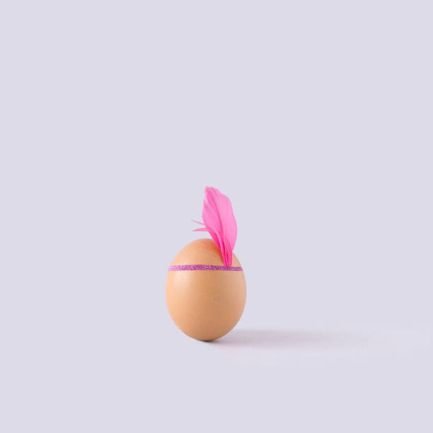 istock Egg with headband and pink feather on pastel grey background. Minimal retro concept. 1309884616