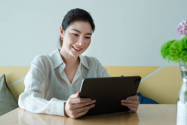 istock Smiling young asian woman entrepreneur checking order by  digital tablet while sitting at her home office. Work From Home concept. 1309884643