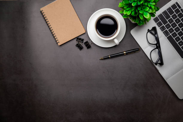 istock Top view desk,Modern office desk Workspace with laptop computer, coffee cup, glasses,notebook and office supplies for Working background concept. 1309888046
